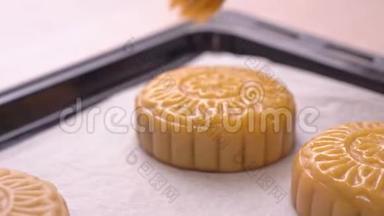 中秋节制作月饼的过程-妇女在烘焙前在糕点表面刷蛋液。 节日自制